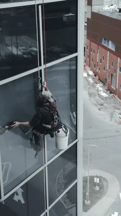 Hombre limpiando en altura los cristales de un edificio